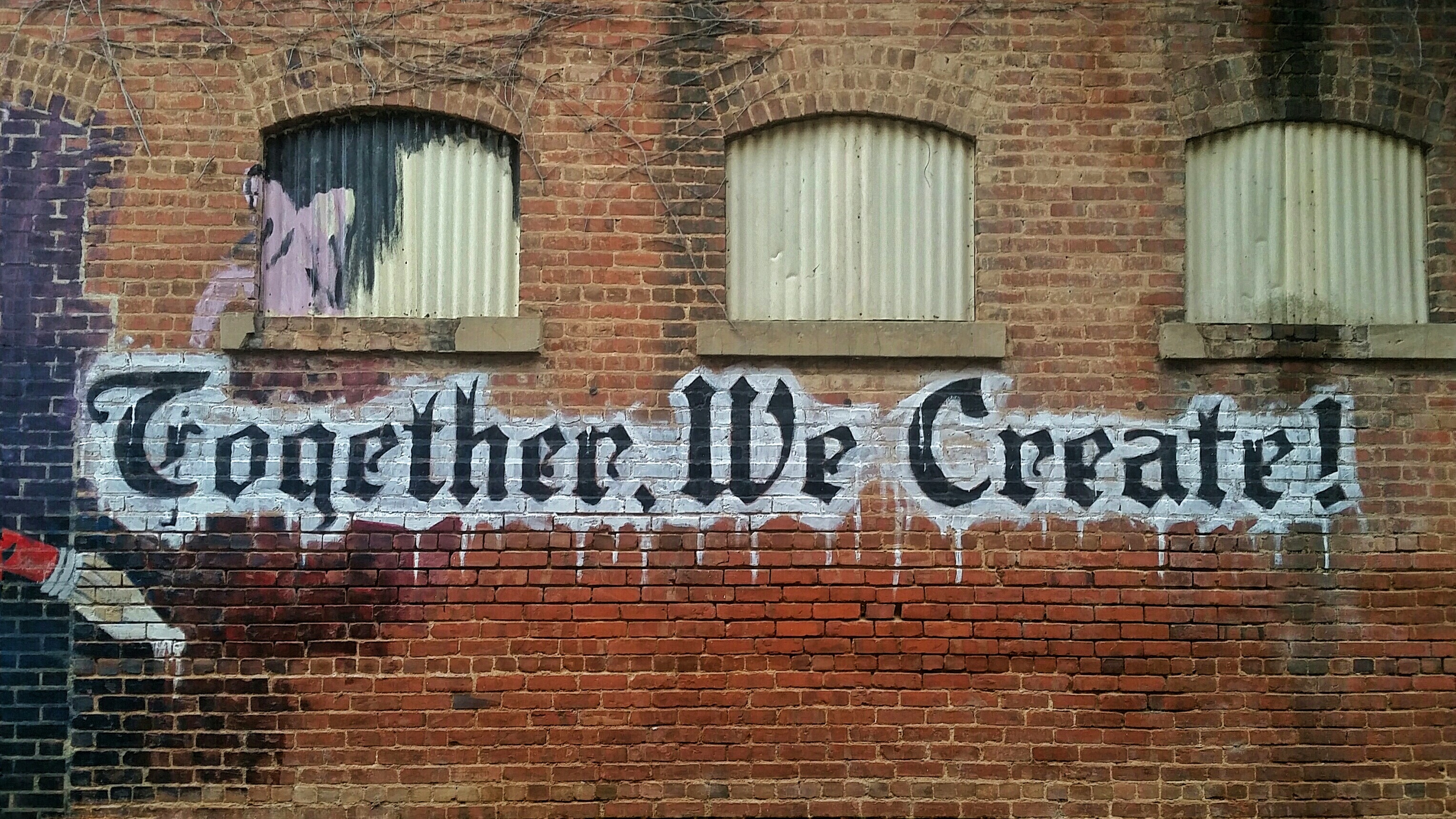 Brick wall with "We create together" grafitti