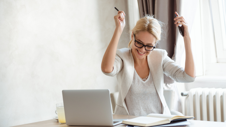 a lady working on her laptop celebrating a win